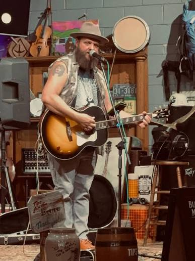 Brandon Butler performing with his acoustic guitar and singing into a microphone